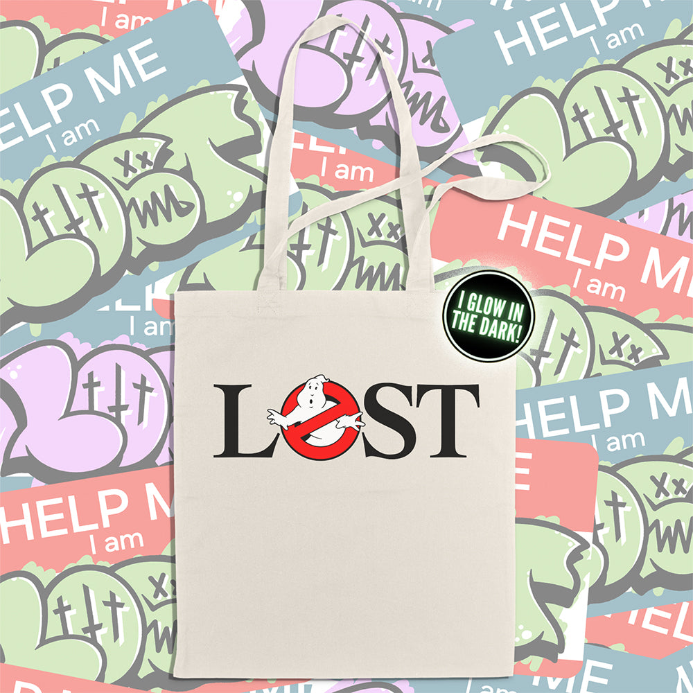 The LOSTBUSTERS tote bag features a surprised looking ghost trapped in the O of the word LOST and vaguely resembling the original Ghostbusters logo. The crisp image is screen printed on a natural canvas tote bag. A wall of colorful graffiti stickers creates a vibrant background for the tote bag on display.